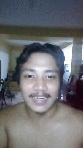 A Shirtless Man With A Mustache Is Smiling And Looking At The Camera GIF