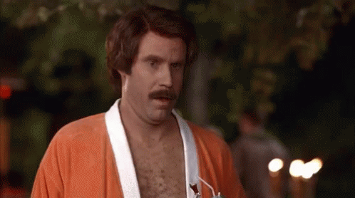 A Shirtless Man With A Mustache Is Wearing An Orange Robe . GIF