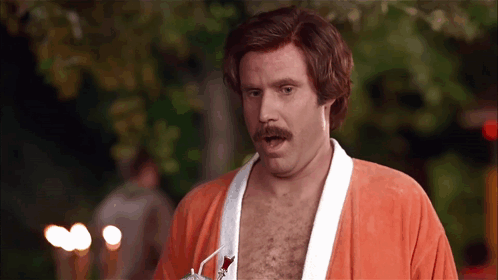 A Shirtless Man With A Mustache Is Wearing An Orange Robe And Sunglasses GIF