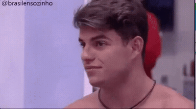 A Shirtless Man With A Necklace Around His Neck Is Looking At Something . GIF