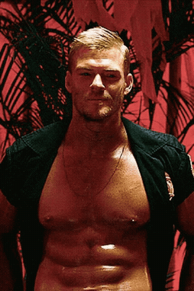 A Shirtless Man With A Palm Tree In The Background Is Wearing A Black Shirt GIF