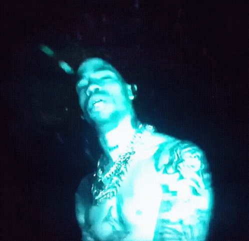 A Shirtless Man With A Tattoo On His Arm Is Lit Up In Blue Light GIF