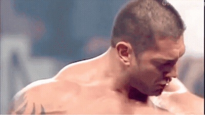 A Shirtless Man With A Tattoo On His Arm Is Standing In A Ring . GIF