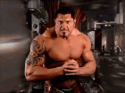 A Shirtless Man With A Tattoo On His Arm Stands With His Arms Crossed GIF