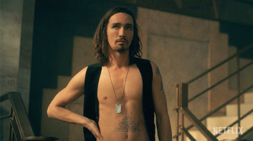 A Shirtless Man With A Tattoo On His Chest Is Standing In Front Of A Netflix Sign GIF