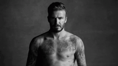 A Shirtless Man With A Tattoo On His Chest Is Standing Next To Another Shirtless Man . GIF