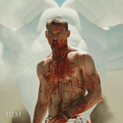 A Shirtless Man With Blood On His Torso Is Standing In Front Of A Statue With The Word Him Written On It GIF
