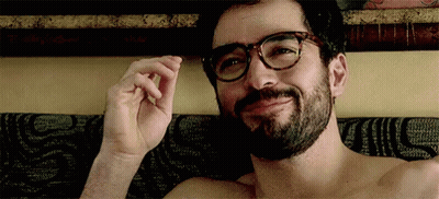 A Shirtless Man With Glasses And A Beard Is Laying On A Bed . GIF