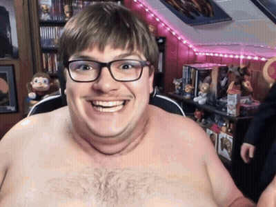 A Shirtless Man With Glasses Is Smiling In A Room GIF