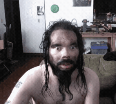 A Shirtless Man With Long Hair And A Beard Has A Tattoo On His Arm That Says ' A ' On It GIF