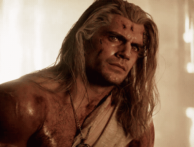 A Shirtless Man With Long Hair And A Necklace Around His Neck GIF