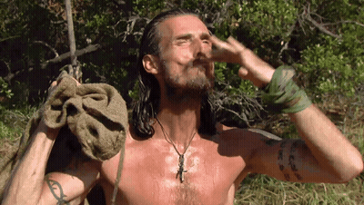 A Shirtless Man With Long Hair Is Holding A Towel Over His Head GIF