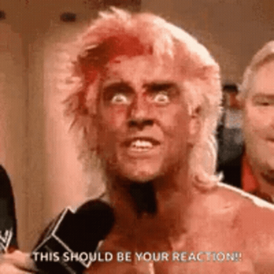 A Shirtless Man With Red Hair Is Talking Into A Microphone . GIF