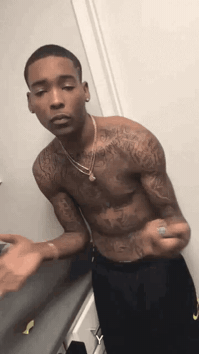 A Shirtless Man With Tattoos On His Arms And Chest Is Standing In A Room . GIF