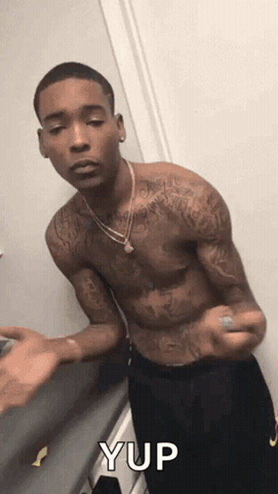 A Shirtless Man With Tattoos On His Arms And Chest Is Standing In A Room . GIF