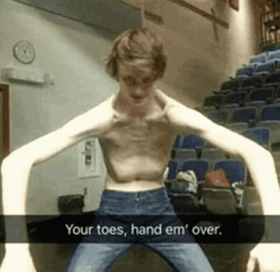 A Shirtless Man With Very Long Arms Is Standing In Front Of A Row Of Blue Seats . GIF