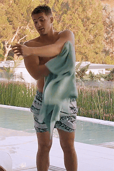 A Shirtless Man Wrapped In A Towel Stands By A Pool GIF