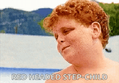 A Shirtless Redheaded Step-Child Is Standing In Front Of A Body Of Water With Mountains In The Background GIF