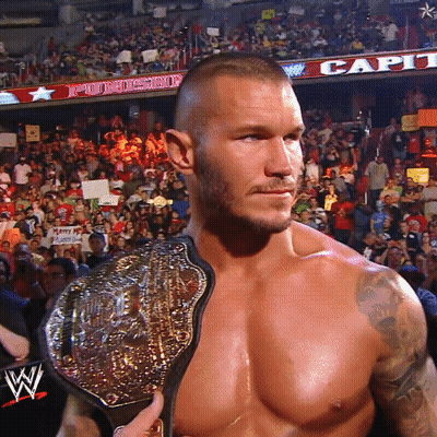 A Shirtless Wrestler Holds A Wrestling Belt In Front Of A Crowd GIF