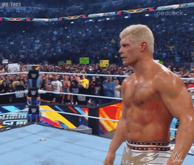 A Shirtless Wrestler In A Wrestling Ring With A Crowd Behind Him GIF