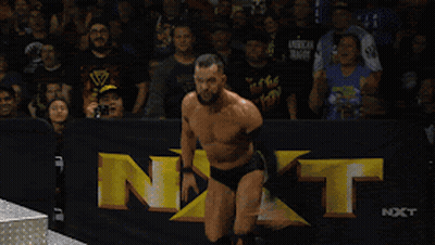 A Shirtless Wrestler In A Wrestling Ring With Nxt Written On The Wall Behind Him GIF