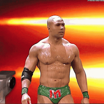 A Shirtless Wrestler In Green Underwear With The Letter M On His Belt GIF