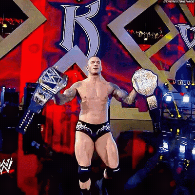 A Shirtless Wrestler Is Holding A Wrestling Championship Belt GIF