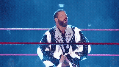A Shirtless Wrestler Is In A Wrestling Ring With His Arms Outstretched . GIF
