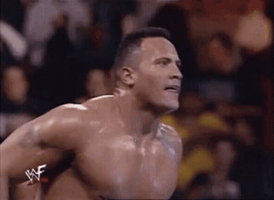 A Shirtless Wrestler Is Jumping In The Air During A Match In Front Of A Crowd . GIF