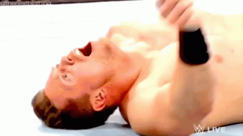 A Shirtless Wrestler Is Laying On His Back With His Mouth Open GIF