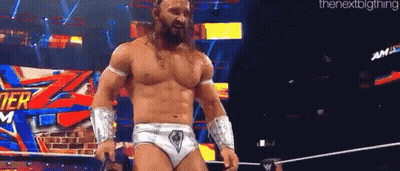 A Shirtless Wrestler Is Standing In A Ring Holding A Microphone . GIF