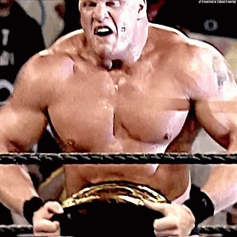 A Shirtless Wrestler Is Standing In A Ring Holding A Wrestling Belt . GIF