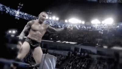 a shirtless wrestler is standing in a ring with a crowd watching .