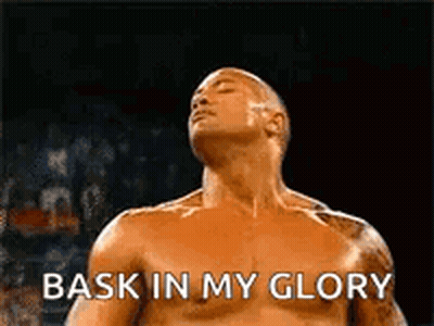A Shirtless Wrestler Is Standing In A Ring With His Eyes Closed And The Words `` Bask In My Glory '' . GIF