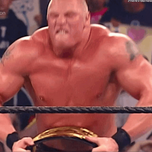 A Shirtless Wrestler Is Standing In A Wrestling Ring Holding A Championship Belt . GIF