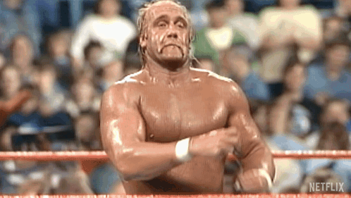 A Shirtless Wrestler Is Standing In A Wrestling Ring With His Hands Crossed . GIF