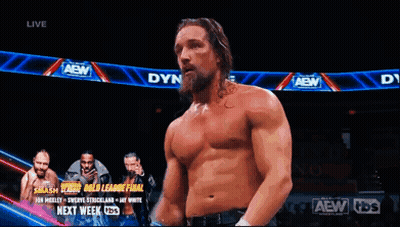 A Shirtless Wrestler Is Standing In Front Of A Banner That Says Aew GIF
