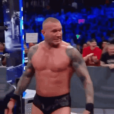 A Shirtless Wrestler Is Standing In Front Of A Crowd In A Ring . GIF