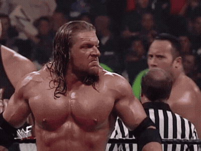 A Shirtless Wrestler Is Standing In Front Of A Referee In A Wrestling Match . GIF
