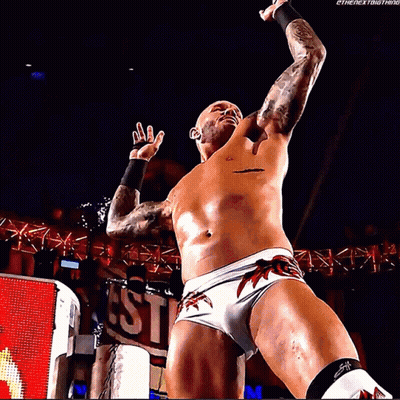 A Shirtless Wrestler Is Standing In Front Of A Sign That Says ' Ethenextbigthing ' GIF