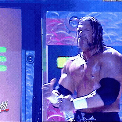 A Shirtless Wrestler Is Standing In Front Of A Sign That Says ' The Next Thing ' On It GIF