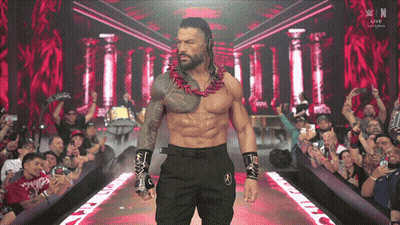 A Shirtless Wrestler Is Walking Down A Ramp With A Crowd Behind Him And A Sign That Says W In The Background GIF