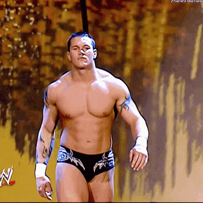 A Shirtless Wrestler Is Walking On A Stage With A W Logo In The Corner GIF