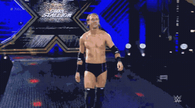 A Shirtless Wrestler Stands In A Dark Room With A Wwe Logo In The Background GIF