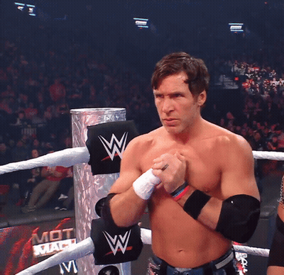 A Shirtless Wrestler Stands In A Ring With A Sign That Says Mot Mach On It GIF