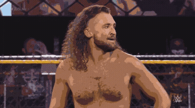 A Shirtless Wrestler Stands In A Ring With A Wrestling Logo In The Background GIF