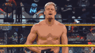 A Shirtless Wrestler Stands In A Wrestling Ring With The Letters W On The Bottom Right Corner GIF