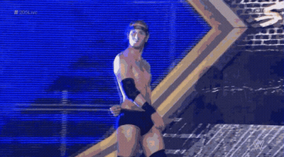 A Shirtless Wrestler Stands In Front Of A Brick Wall With The Hashtag # 20Live On The Bottom GIF