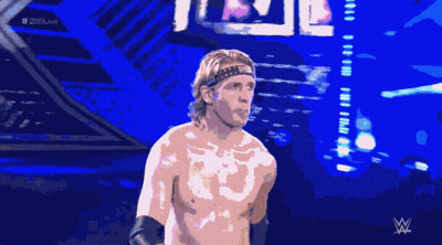 A Shirtless Wrestler Stands In Front Of A Crowd With The Hashtag # 205Live On The Bottom GIF