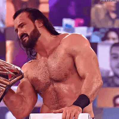A Shirtless Wrestler With A Beard Is Holding A Wrestling Championship Belt GIF